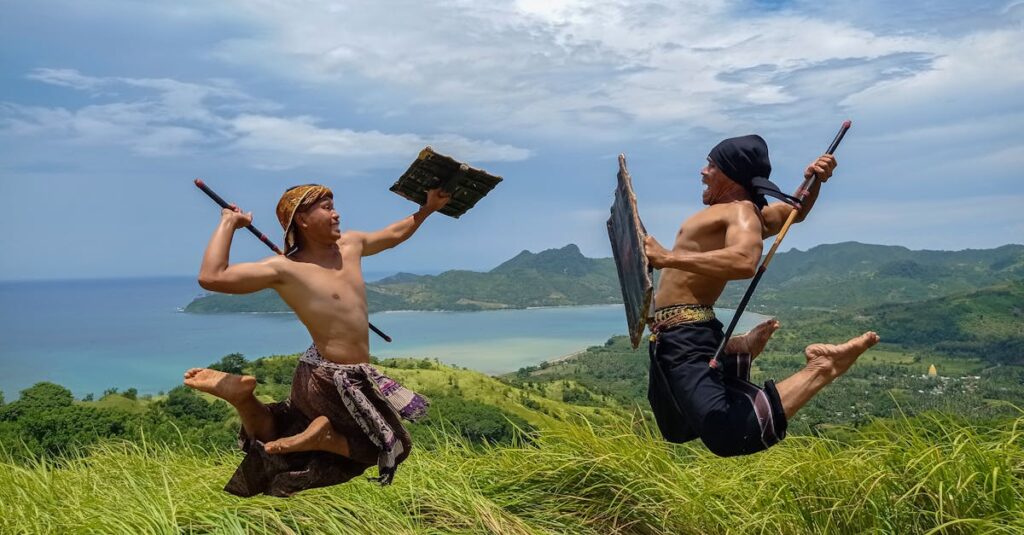 Men in a traditional Sasak warrior dance, leaping midair in scenic Lombok, Indonesia.